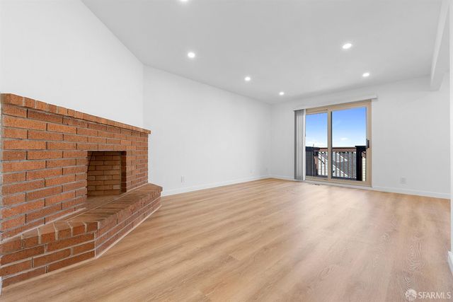 a view of empty room with wooden floor and fireplace
