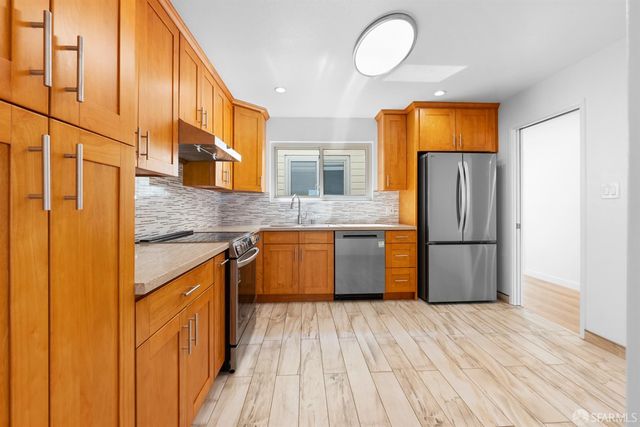 a kitchen with stainless steel appliances granite countertop a refrigerator a stove and a wooden floors