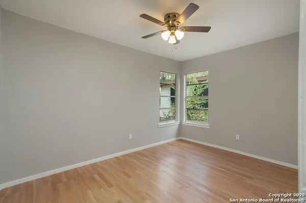 a view of an empty room with window and wooden floor