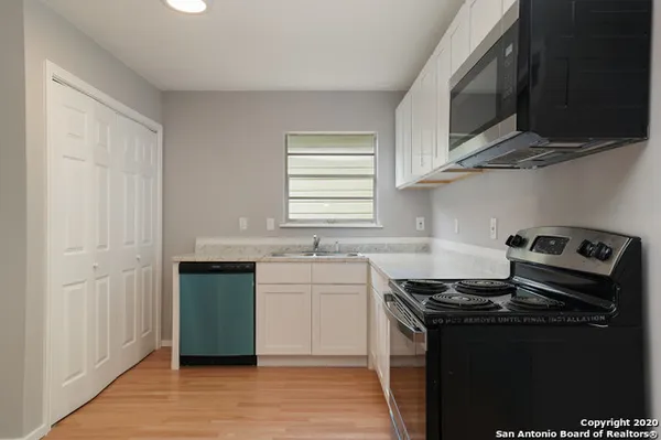 a kitchen with cabinets appliances a sink and a window