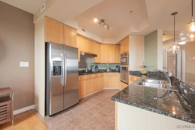 a large kitchen with kitchen island a large counter top stainless steel appliances and cabinets