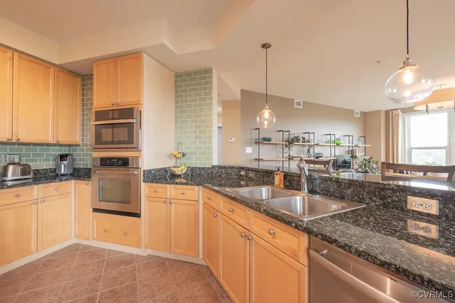 a large kitchen with granite countertop a sink a counter space appliances and cabinets