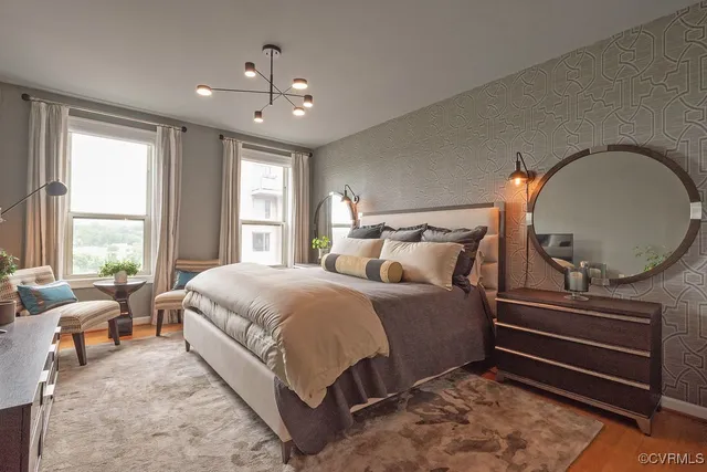 a spacious bedroom with a bed a dresser and large windows