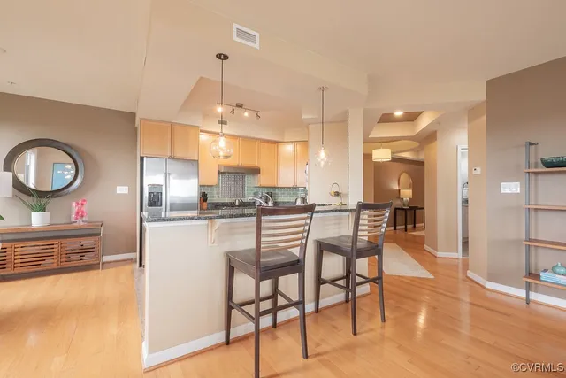 a kitchen with stainless steel appliances kitchen island granite countertop a table chairs and a refrigerator