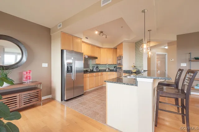 a view of a kitchen with kitchen island stainless steel appliances a refrigerator a stove a sink a dining table and chairs