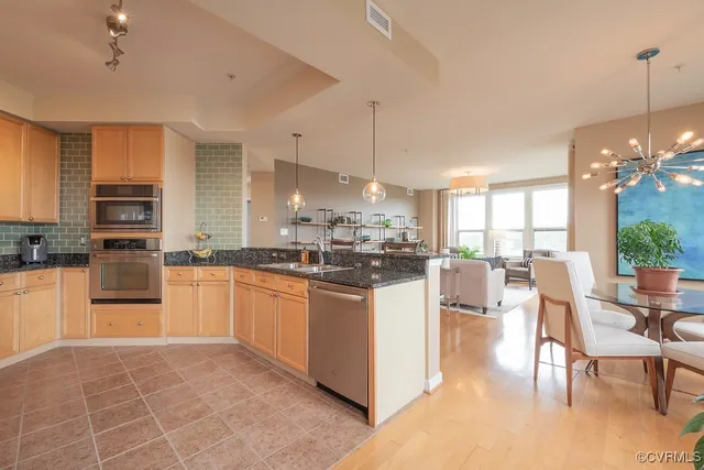 a kitchen with stainless steel appliances granite countertop a stove top oven a sink dishwasher and white cabinets with wooden floor