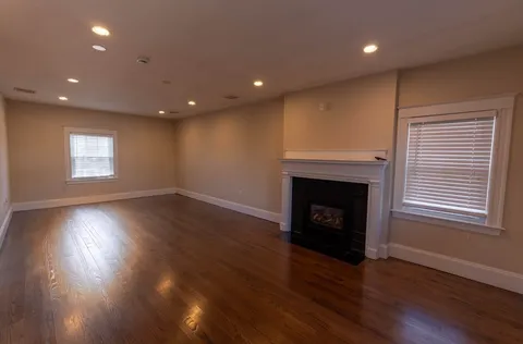 an empty room with wooden floor and fireplace