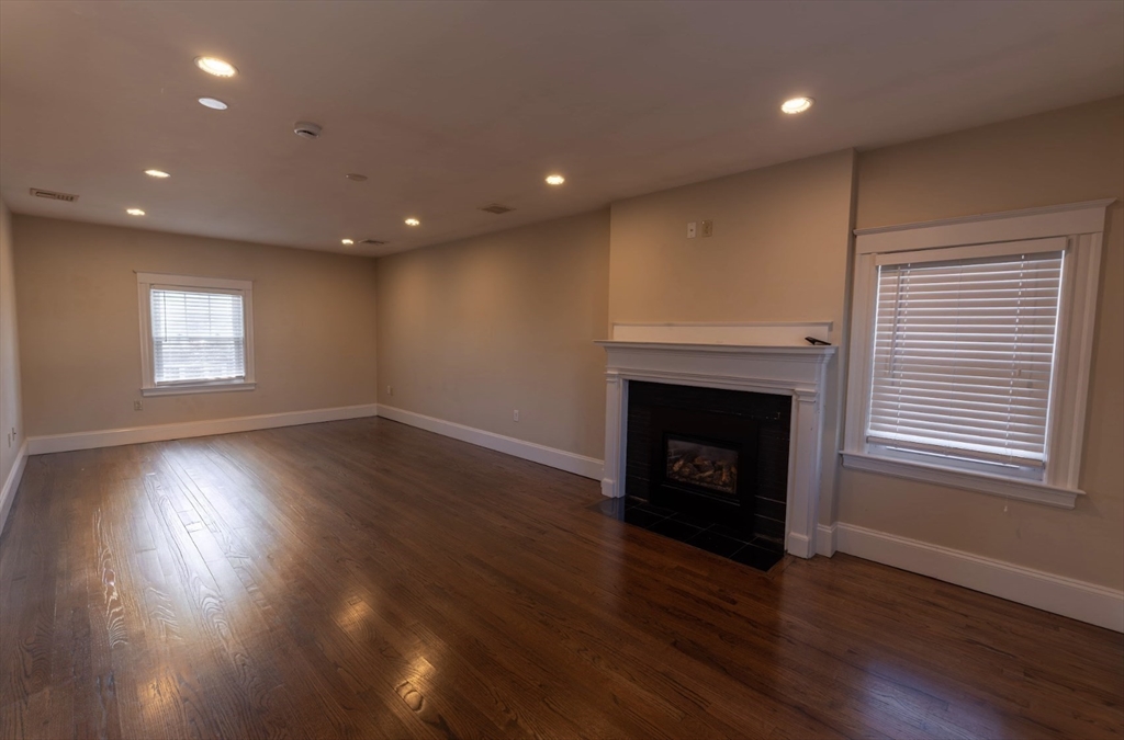 1000 South Street Boston, MA 02131 - Photo 14 of 22 an empty room with wooden floor and fireplace