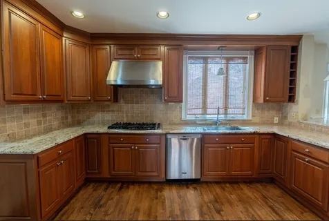 a kitchen with stainless steel appliances granite countertop wooden cabinets a sink and dishwasher with wooden floor