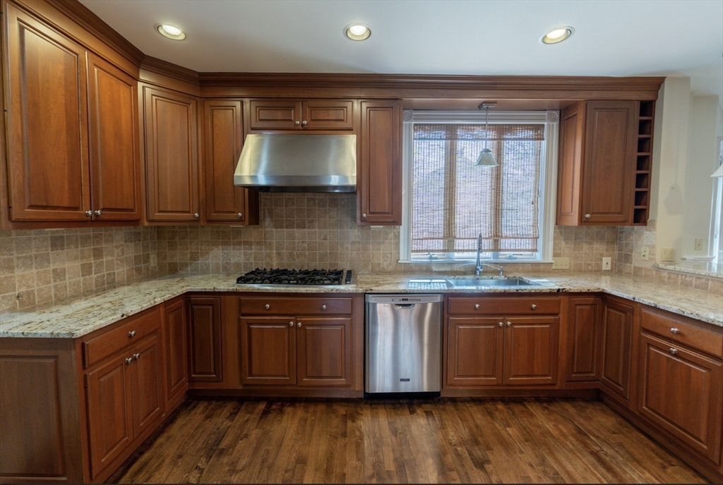 1000 South Street Boston, MA 02131 - Photo 10 of 22 a kitchen with stainless steel appliances granite countertop wooden cabinets a sink and dishwasher with wooden floor