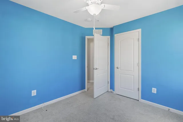 an empty room with closet and a chandelier fan