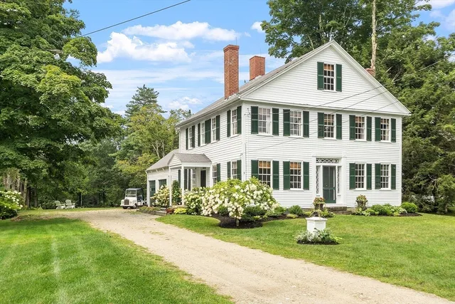 a front view of a house with a yard and potted plants