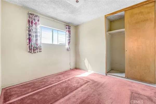 a view of an empty room with window and closet