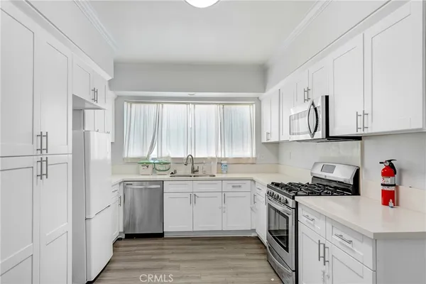 a kitchen with stainless steel appliances granite countertop white cabinets sink and white appliances