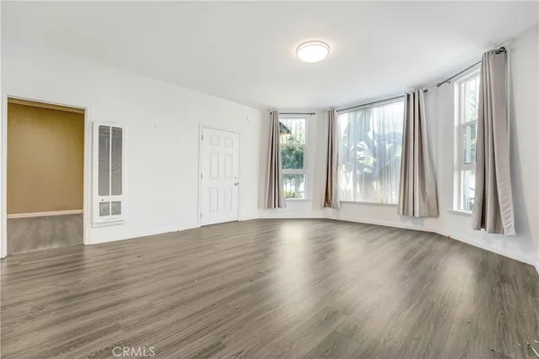 an empty room with wooden floor and windows with curtains view