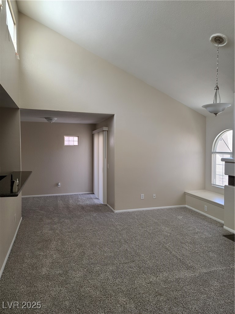 9325 West Desert Inn Road, Unit 233 Las Vegas, NV 89117 - Photo 2 of 10 Front entry, Dining room, with view of living room with carpet flooring and high vaulted ceiling