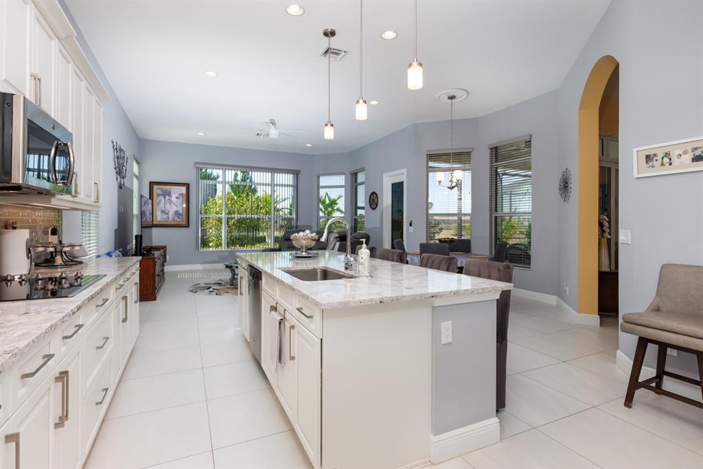 21864 Southwest Tivolo Way Port St. Lucie, FL 34986 - Photo 15 of 40 a large kitchen with kitchen island a large counter space a sink stainless steel appliances and cabinets