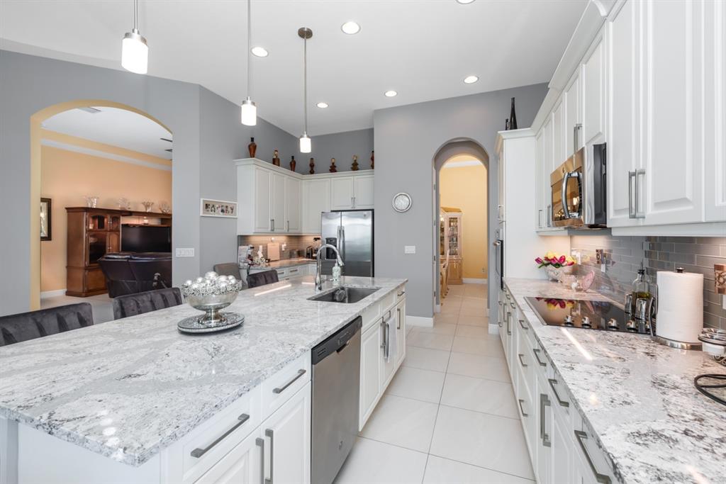 21864 Southwest Tivolo Way Port St. Lucie, FL 34986 - Photo 17 of 40 a large kitchen with kitchen island a large counter top space a sink stainless steel appliances and cabinets