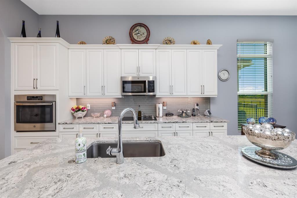 21864 Southwest Tivolo Way Port St. Lucie, FL 34986 - Photo 19 of 40 a kitchen with stainless steel appliances a sink a stove a microwave a sink and cabinets