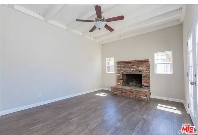a view of an empty room with wooden floor a fireplace and a window