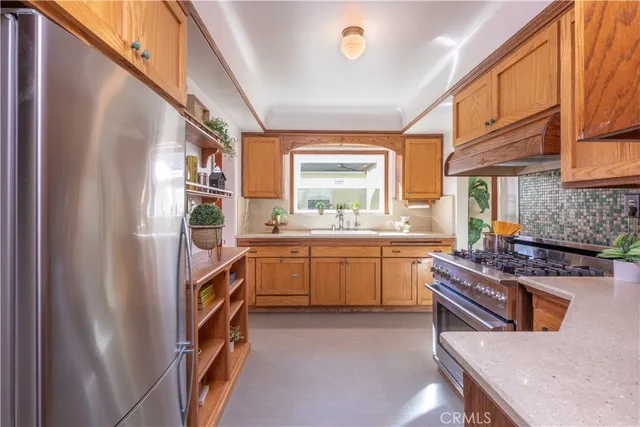 a kitchen with stainless steel appliances granite countertop a refrigerator a sink dishwasher a stove and white countertops with wooden floor