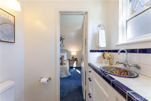 a kitchen with a sink and a stove with white cabinets