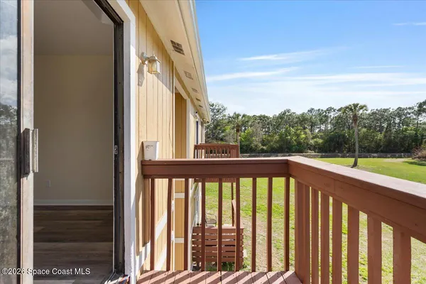 a view of a balcony with yard and trees in the background
