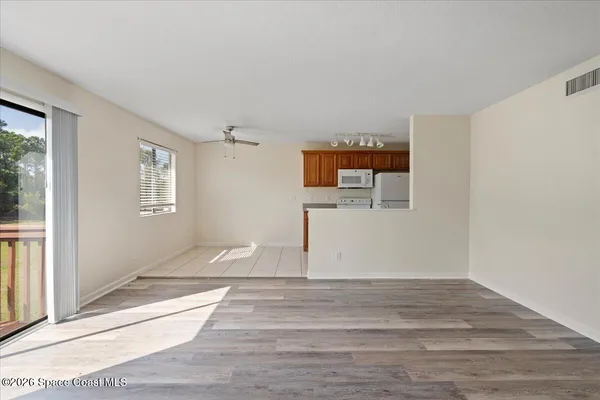 a view of empty room with wooden floor and fan