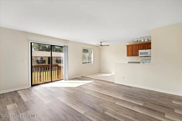 a view of an empty room with wooden floor and a window