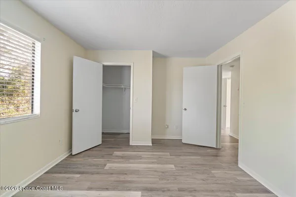 a view of an empty room with wooden floor and window