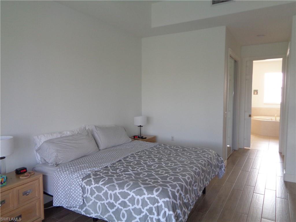 709 Regency Reserve Circle, Unit 6003 Naples, FL 34119 - Photo 23 of 44 a bedroom with a bed and wooden floor
