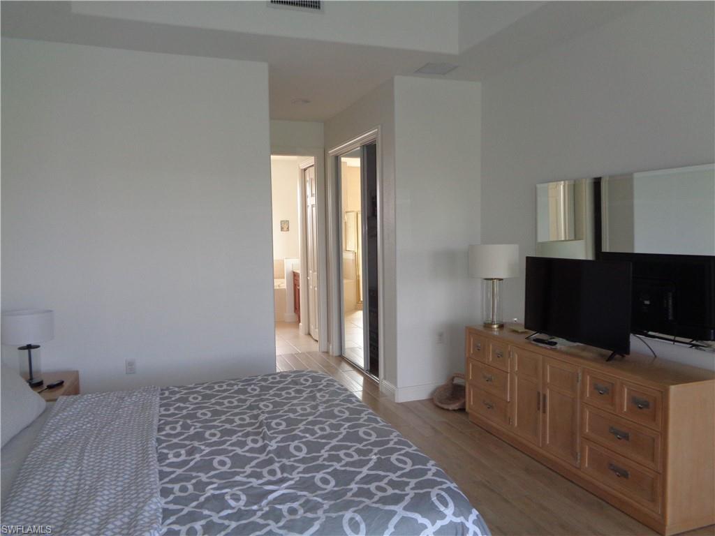 709 Regency Reserve Circle, Unit 6003 Naples, FL 34119 - Photo 24 of 44 a bedroom with a bed and flat screen tv