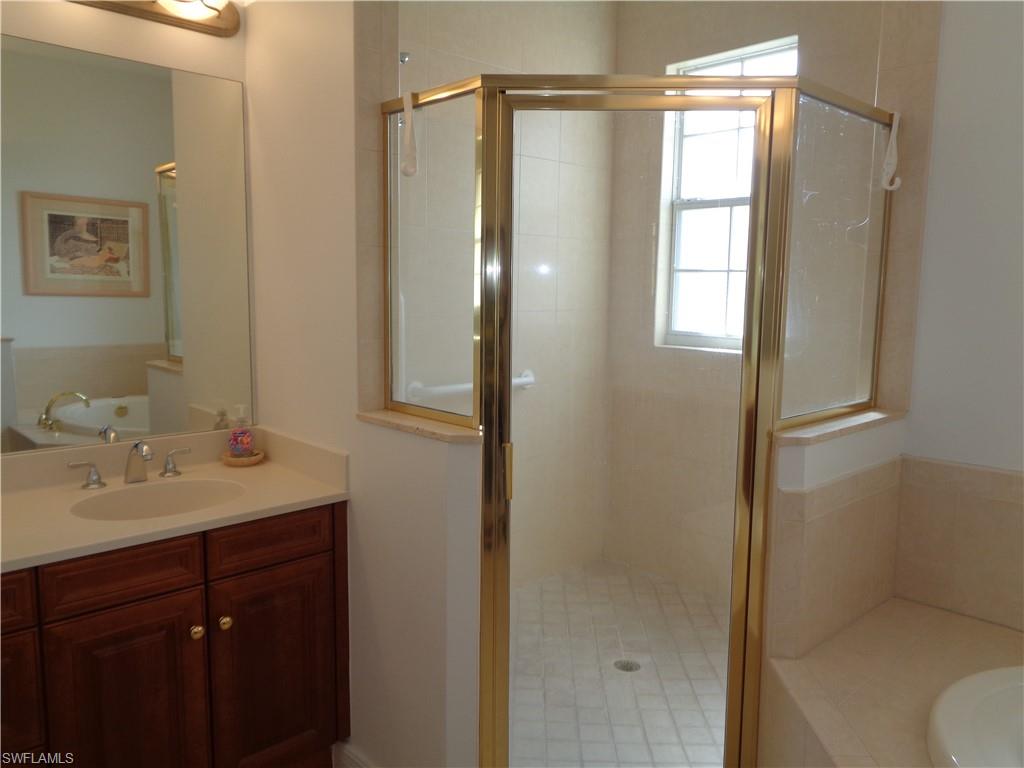 709 Regency Reserve Circle, Unit 6003 Naples, FL 34119 - Photo 26 of 44 a bathroom with a shower sink vanity and mirror