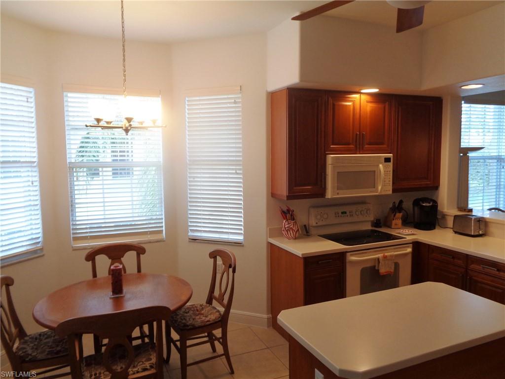 709 Regency Reserve Circle, Unit 6003 Naples, FL 34119 - Photo 7 of 44 a kitchen with a table chairs sink and microwave