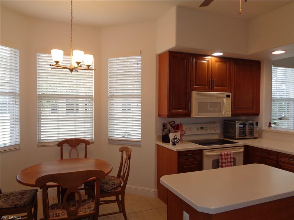 709 Regency Reserve Circle, Unit 6003 Naples, FL 34119 - Photo 8 of 44 Kitchen featuring white appliances, light tile patterned flooring, light countertops, pendant lighting, and a center island