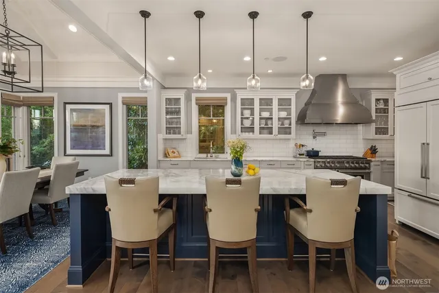 a kitchen with stainless steel appliances a dining table chairs and white cabinets