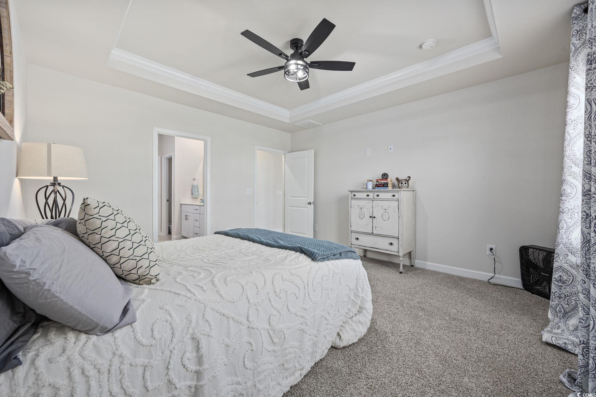 2412 Copper Mdw Loop Longs, SC 29568 - Photo 16 of 40 Bedroom featuring a tray ceiling, crown molding, carpet flooring, ceiling fan, and connected bathroom