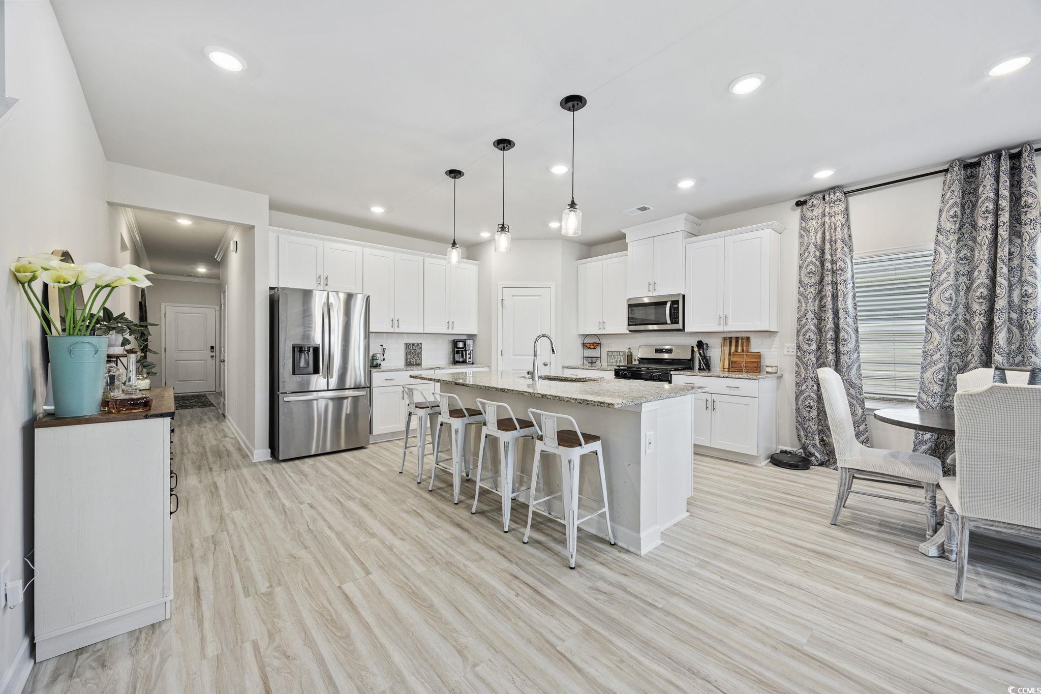 2412 Copper Mdw Loop Longs, SC 29568 - Photo 5 of 40 Kitchen featuring a breakfast bar, appliances with stainless steel finishes, white cabinetry, pendant lighting, and a kitchen island with sink