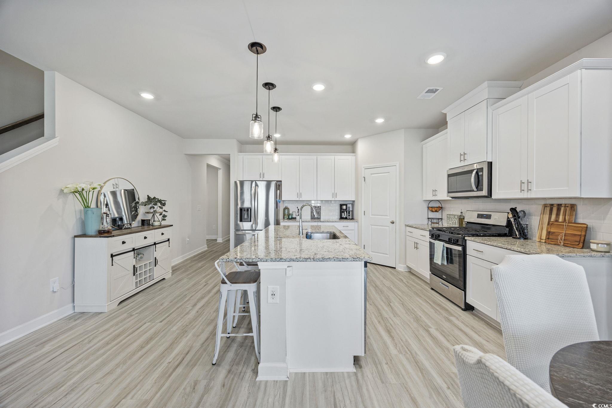 2412 Copper Mdw Loop Longs, SC 29568 - Photo 6 of 40 Kitchen featuring stainless steel appliances, tasteful backsplash, a breakfast bar area, light wood finished floors, and white cabinets