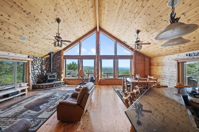a living room with furniture large windows and wooden floor