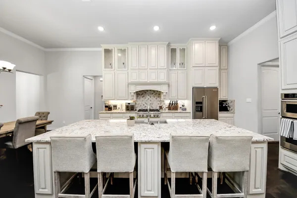 a kitchen with kitchen island granite countertop a dining table chairs cabinets and stainless steel appliances