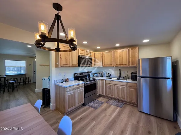 a kitchen with a refrigerator a stove and a dining table with wooden floor