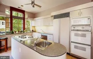 a kitchen with kitchen island white cabinets a sink a stove and a refrigerator