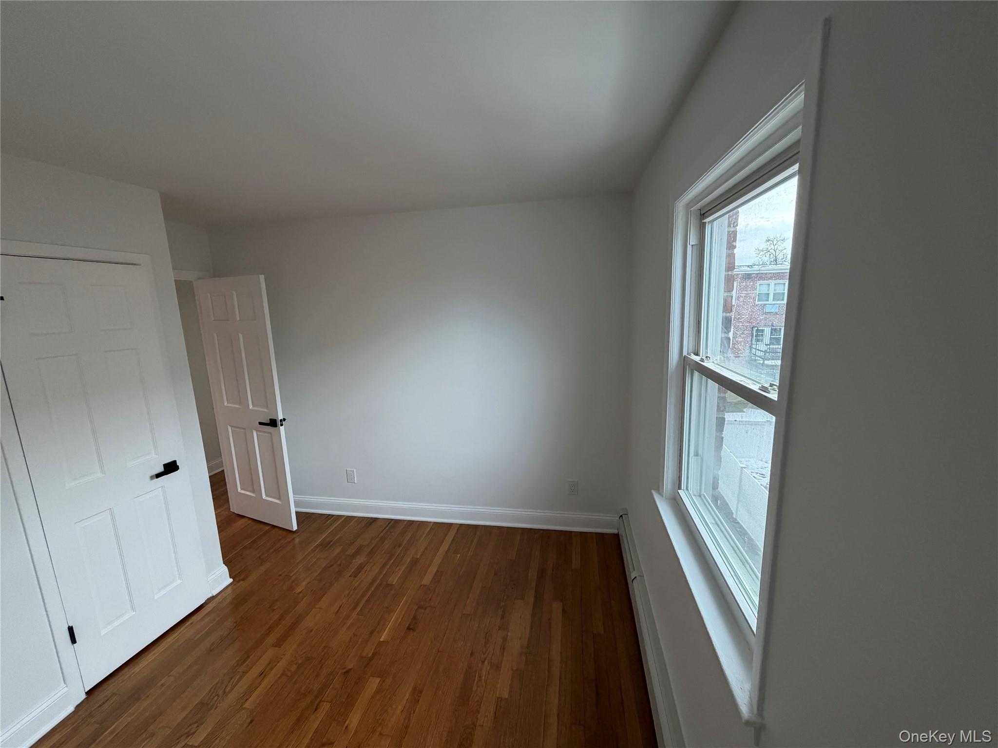 144-50 25th Road Queens, NY 11354 - Photo 13 of 20 an empty room with wooden floor and windows