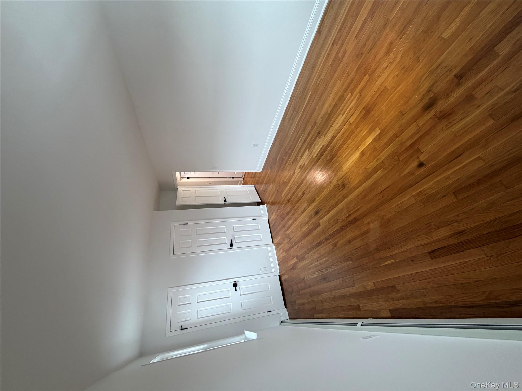 144-50 25th Road Queens, NY 11354 - Photo 16 of 20 a view of an empty room with wooden floor and window