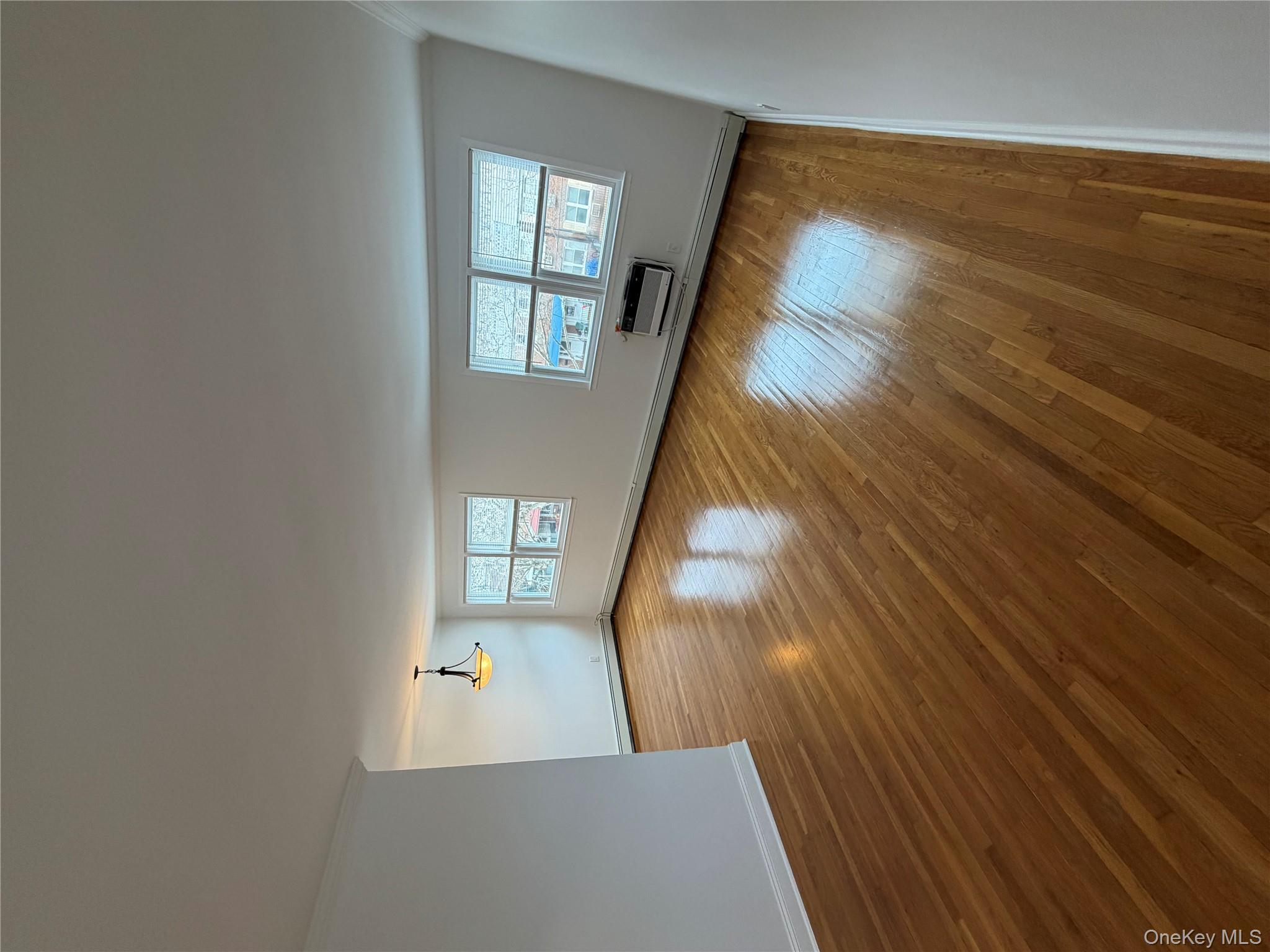 144-50 25th Road Queens, NY 11354 - Photo 4 of 20 an empty room with wooden floor and windows