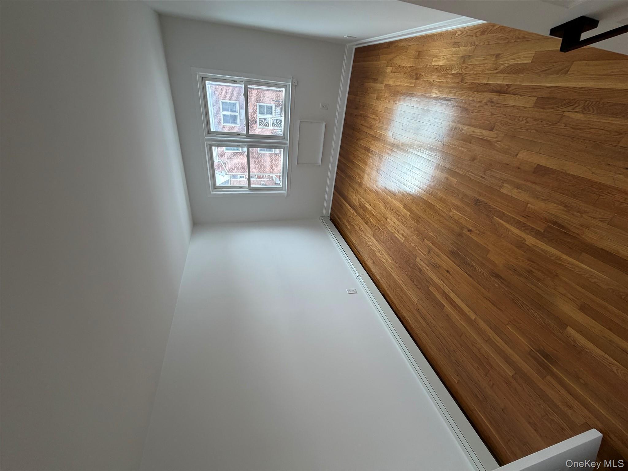 144-50 25th Road Queens, NY 11354 - Photo 8 of 20 an empty room with wooden floor and windows