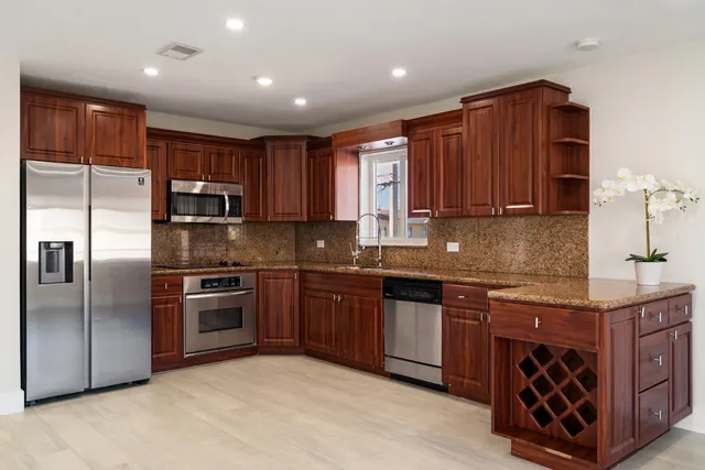 a kitchen with stainless steel appliances granite countertop a stove top oven a sink and dishwasher a refrigerator with wooden cabinets