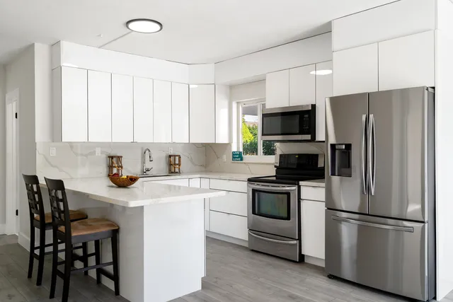 a kitchen with stainless steel appliances a refrigerator stove microwave and white cabinets
