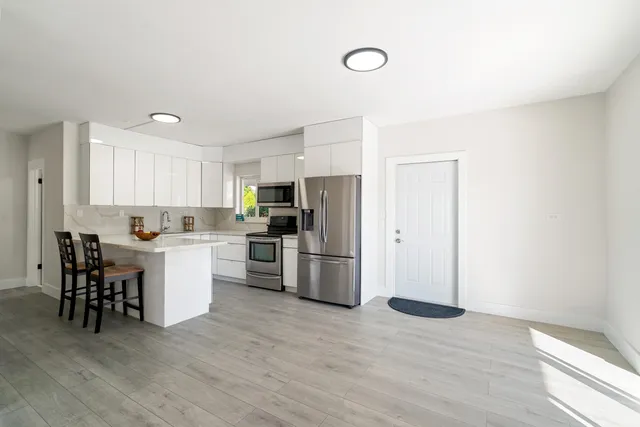 a kitchen with a refrigerator and white cabinets